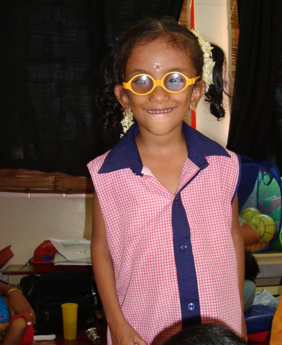 Portrait of a little girl with spectacles smiling at the camera.