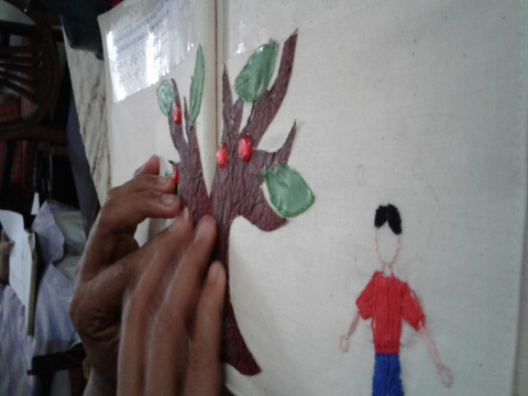 A young girl explores the picture of a girl stretching in an accessible tactile story book